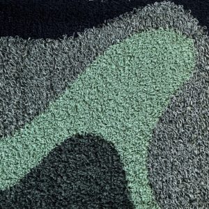 gros plan d'une tapisserie réalisée au punch needle dans des tons verts et noirs